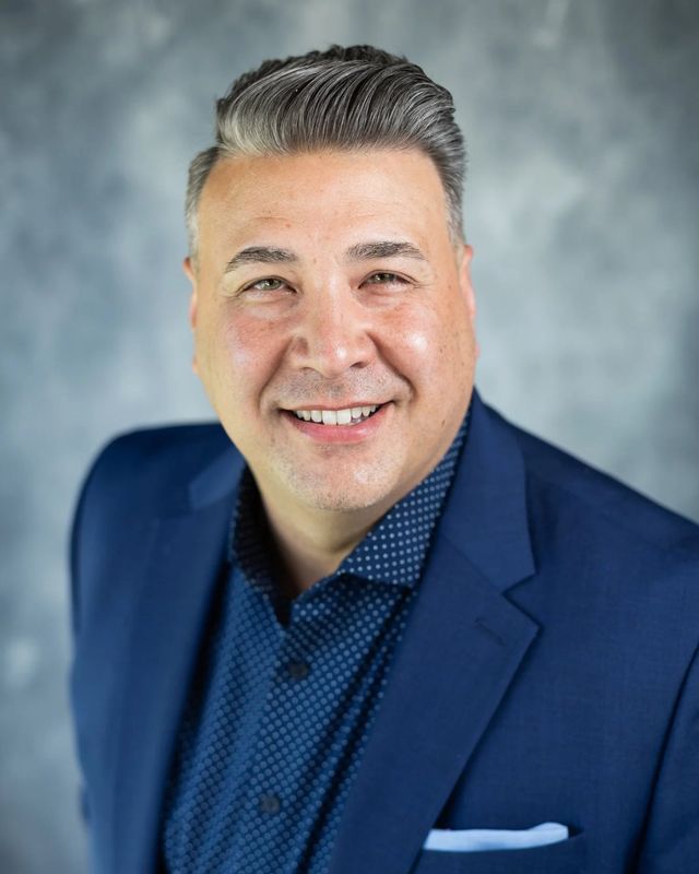 Studio headshot, blue suit, gray backdrop