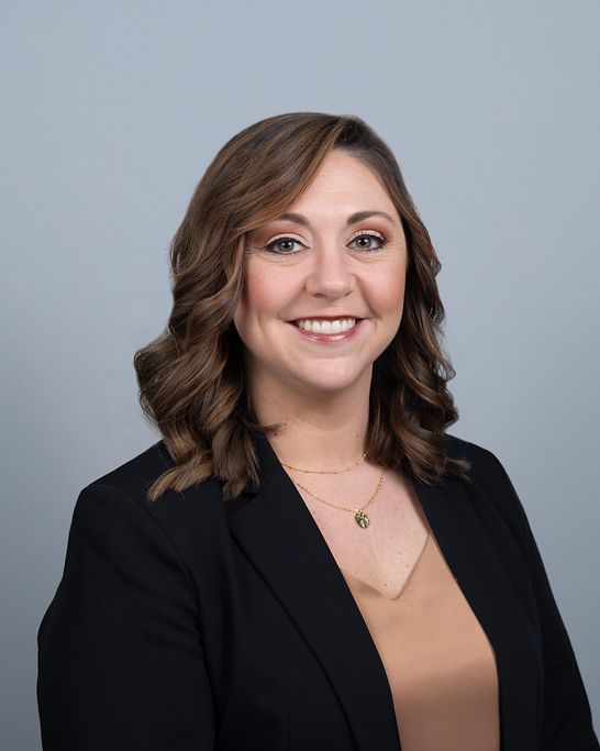 Studio headshot, black blazer, cool gray backdrop